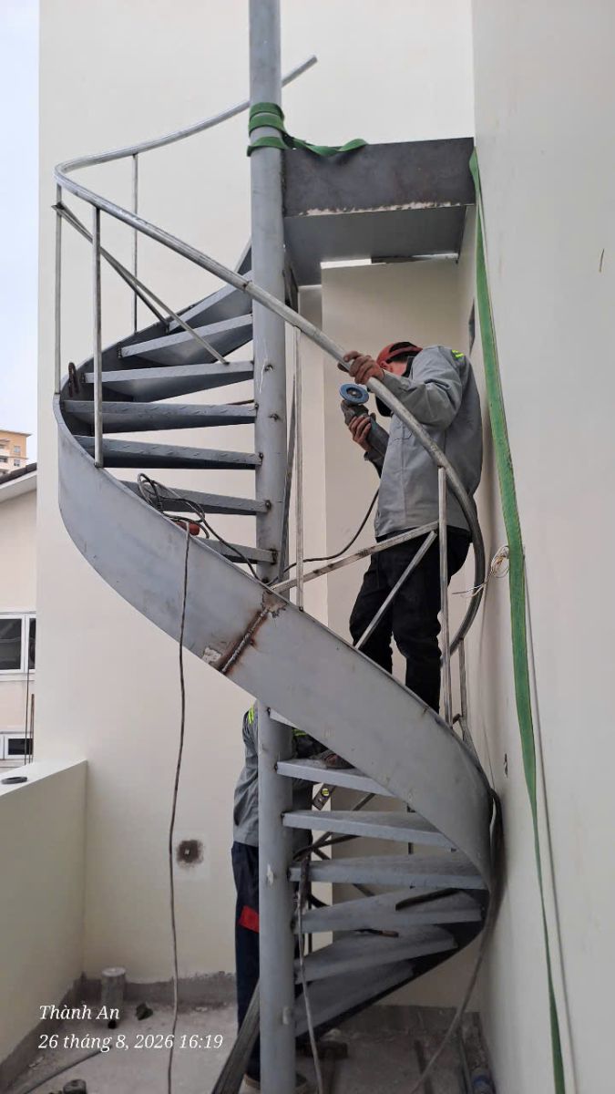 Kỹ thuật viên mài xử lý phẳng mịn các mối hàn trên tay vịn cầu thang sắt xoắn ốc